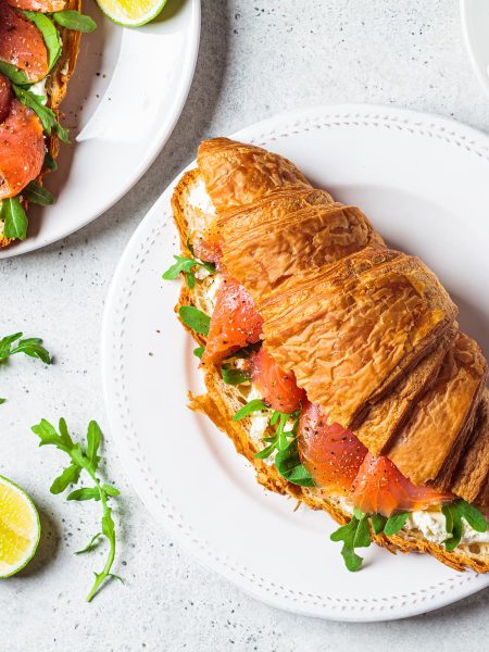 Croissant sandwich with cream cheese salmon on plate.
